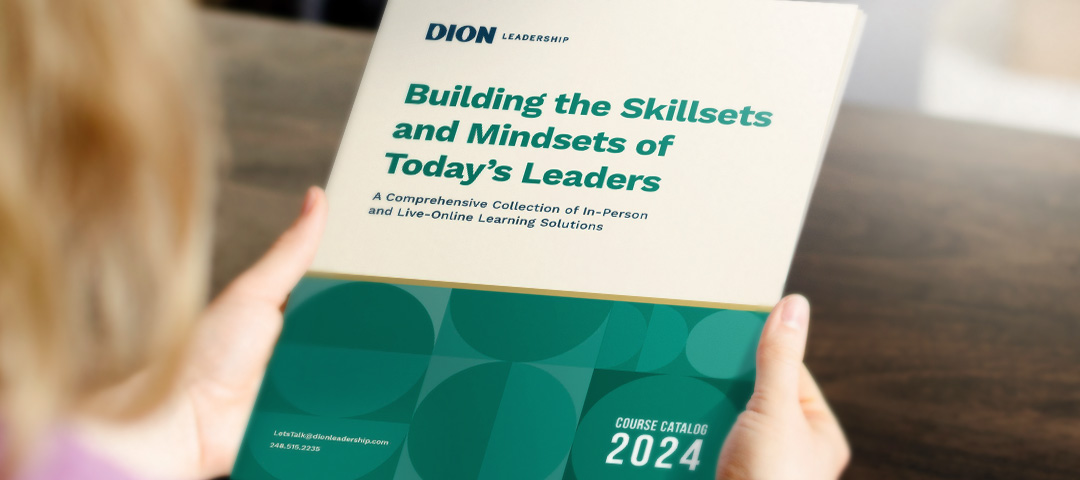 Dion Leadership-Woman Looking at cover of course catalog-2024-Building the Skillsets and Mindsets of Todays Leaders